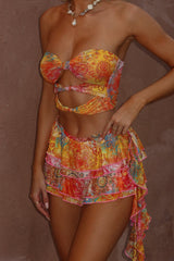 A woman's torso and legs in a brightly colored strapless top and ruffled mini skirt.