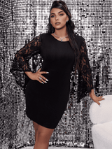 A woman in a black lace-sleeve dress posing against a sequined backdrop.