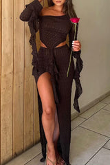 Woman in a brown ruched outfit with a high slit and ruffled sleeves holding a red rose.