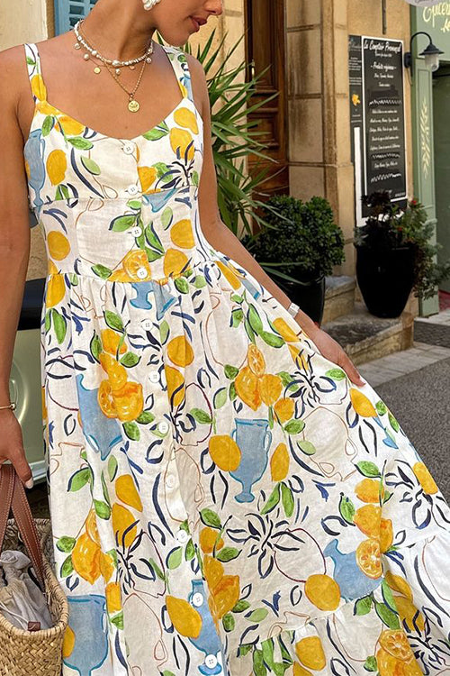 A woman in a lemon-print dress with a tiered skirt, posing outdoors.