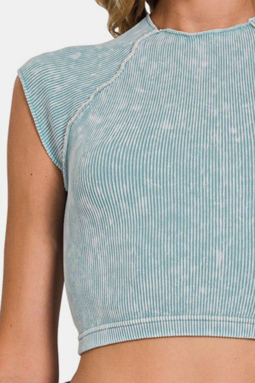 Detail of the shoulder and sleeve of a teal and white acid wash ribbed knit cropped mock neck top.