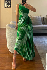 woman in a green and white tie-dye pleated one-shoulder maxi dress standing in a living room