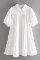 A white tiered babydoll dress with puff sleeves and a collared neckline.