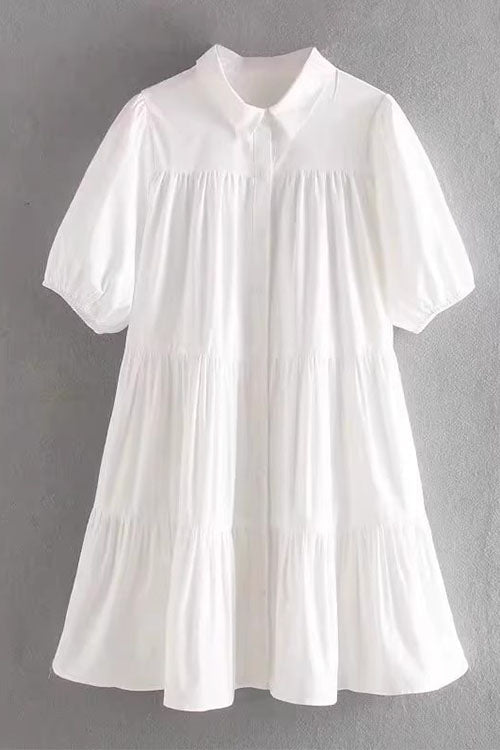 A white tiered babydoll dress with puff sleeves and a collared neckline.