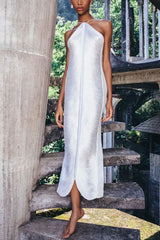 Woman wearing a white ruched halter neck maxi dress