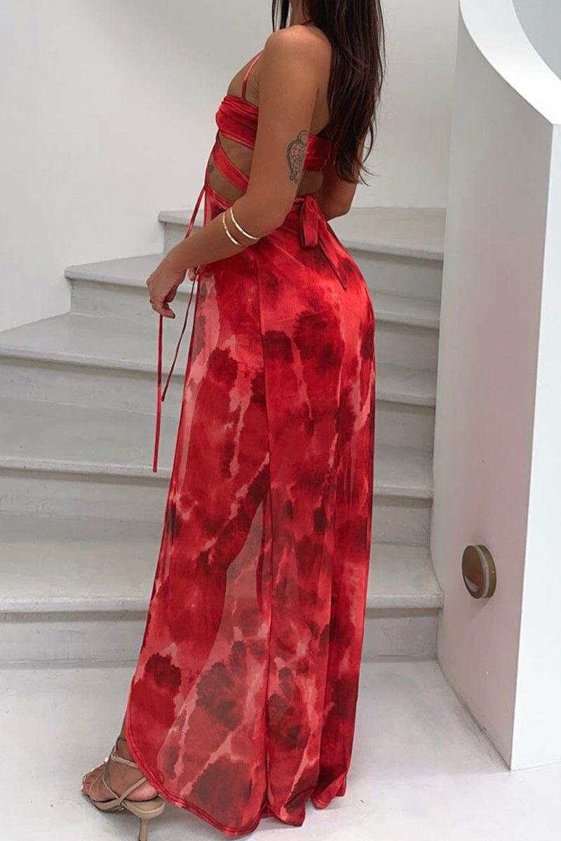 Back view of a woman in a red tie-dye print dress with cut-out details and a sheer maxi skirt.