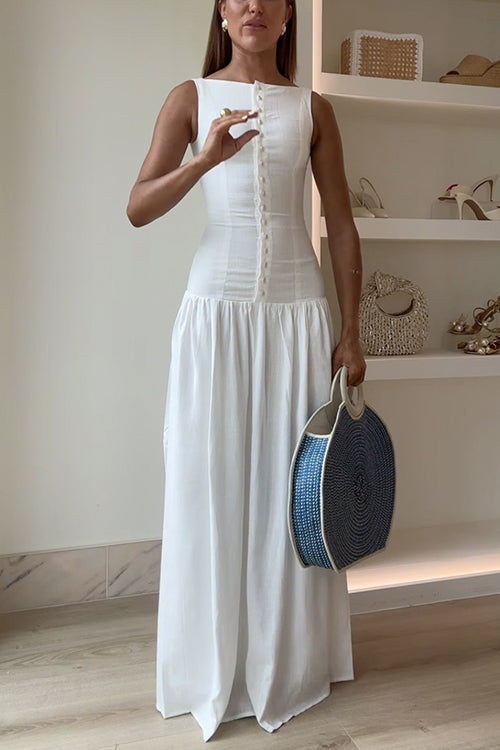 Woman in a white maxi dress adjusting her dress and holding a round blue and white straw bag