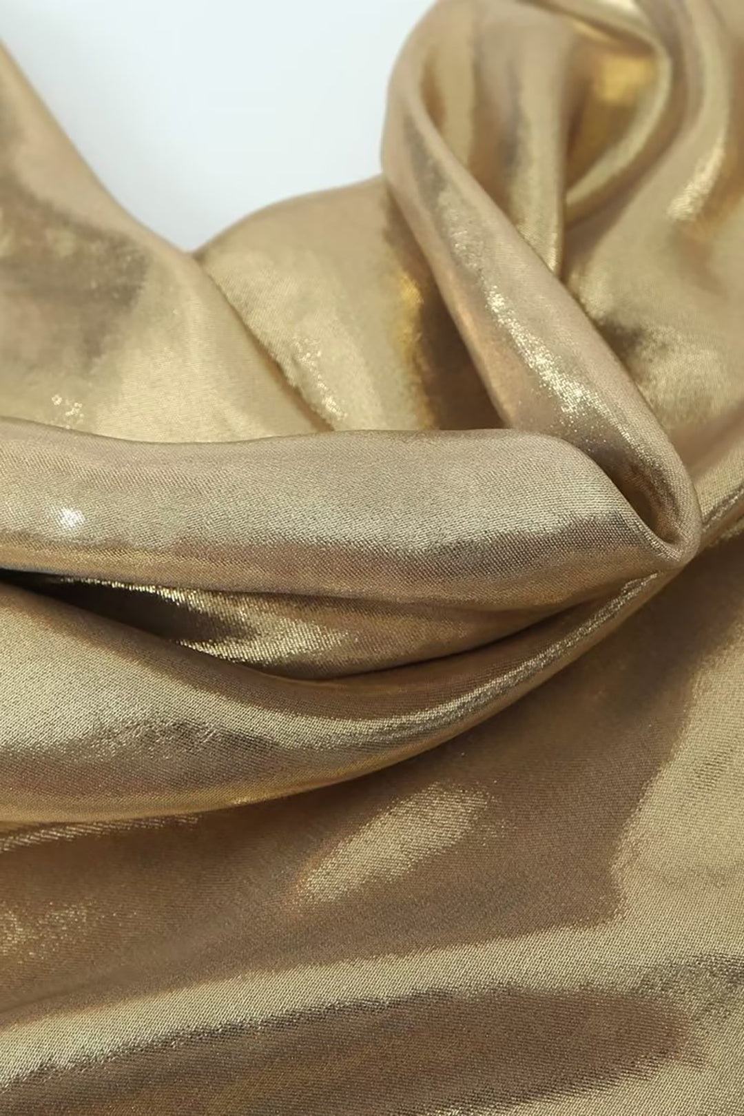 Close-up of the draped metallic gold fabric of a slip dress.