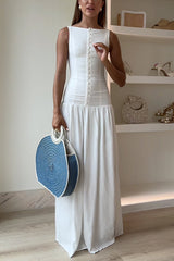 Woman in a white maxi dress and round blue and white straw bag