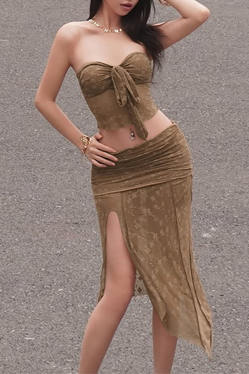 A woman wearing a brown two-piece outfit with a tube top and a ruched skirt.