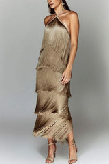 Woman in a gold, tiered fringe halter dress with her arm extended