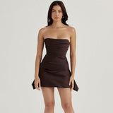 Front view of a woman wearing a strapless dark brown ruched mini dress