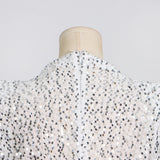 Close-up of the back of the high neckline of a white sequined dress on a mannequin.