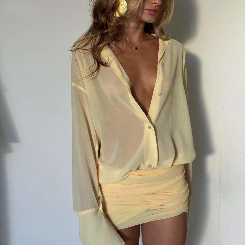 A woman in a pale yellow sheer button-down shirt and ruched mini skirt, focusing on the outfit details.