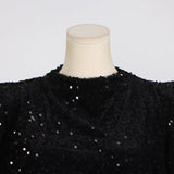 close-up of the high neckline and padded shoulders of a black sequined dress