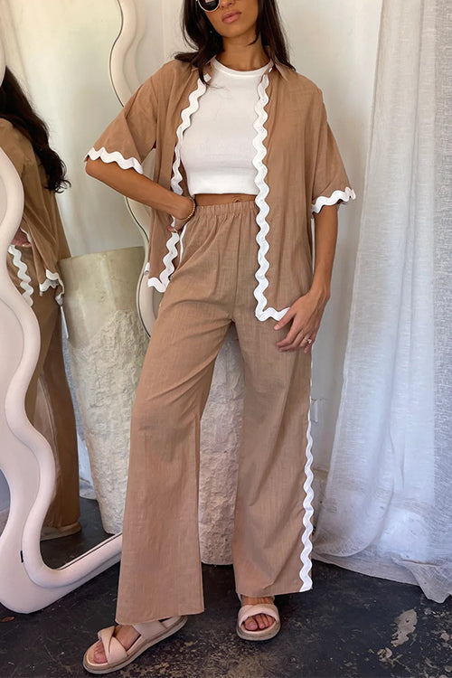 Woman wearing a brown linen-like pajama set with white scalloped trim, paired with a white crop top and beige sandals.