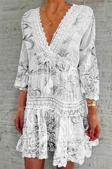 A woman modeling a white bohemian-style dress with black and white floral print and lace trim.