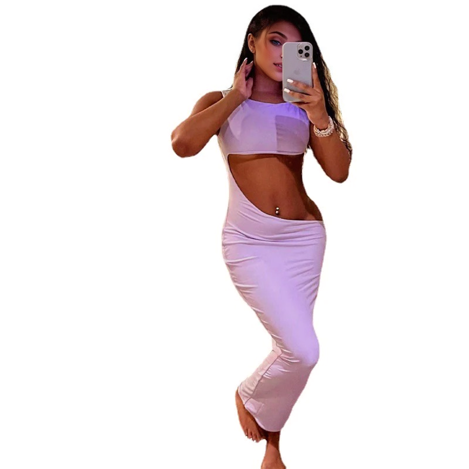 Woman in a lilac two-piece set with a cropped top and a high-waisted, ruched skirt with a side cut-out, shown against a white background.
