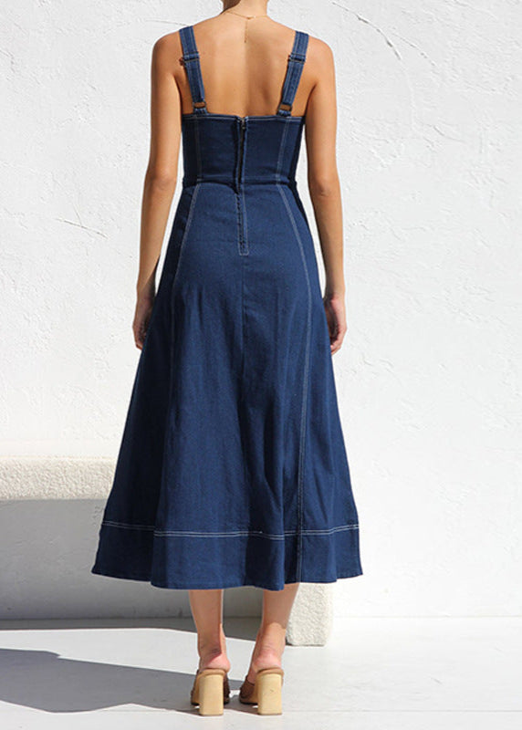 Back view of a woman in a dark blue denim midi dress, showing the zipper closure and the A-line skirt with contrast stitching.