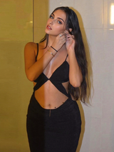 A woman in a black cutout maxi dress is putting on earrings.