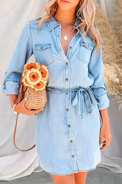 Woman wearing a light blue denim shirt dress with a basket purse