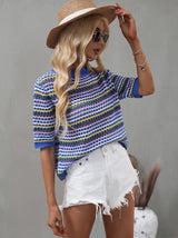 Side view of a woman in a blue and multicolor striped crochet knit top, white distressed denim shorts, and a straw hat.