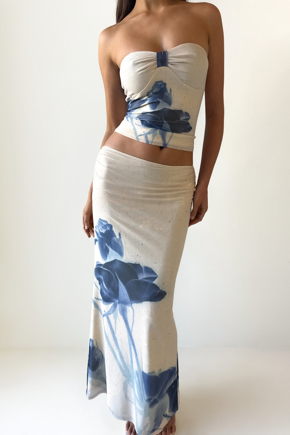 Woman wearing a cream strapless top with a blue floral print and a matching cream maxi skirt with a blue floral print, viewed from the front.