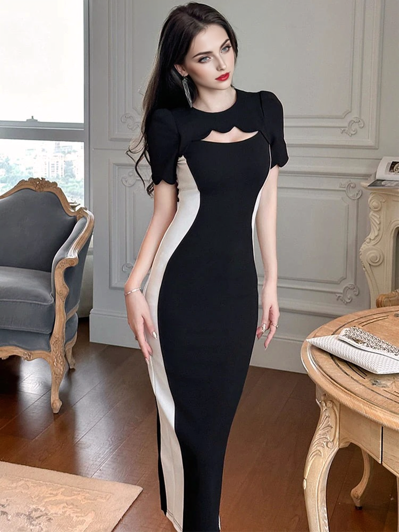 A woman in a black and white sheath dress standing in a room