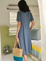 Back view of the woman in the blue dress, holding a straw bag.