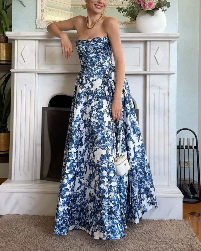 Woman wearing a strapless blue and white floral print ball gown, leaning against a fireplace.
