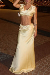 Woman wearing a beige satin two-piece set with a crop top and a flowing maxi skirt.