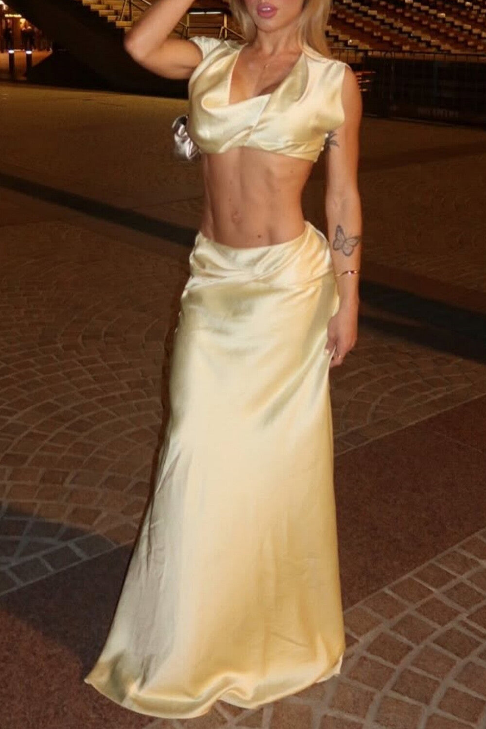 Woman wearing a beige satin two-piece set with a crop top and a flowing maxi skirt.