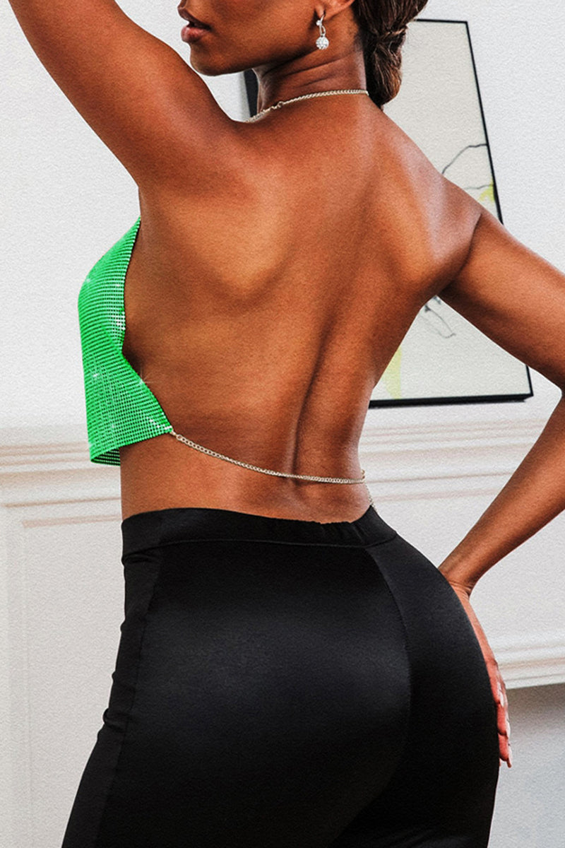 Woman wearing a green metallic mesh halter top with a plunging neckline and black pants, back view.