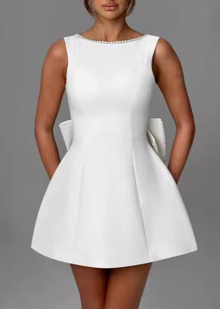 close-up of a white dress with pearl trim and a bow