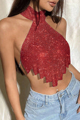 A woman from the side wearing a red halter top with a fringe hem and light-wash jeans.