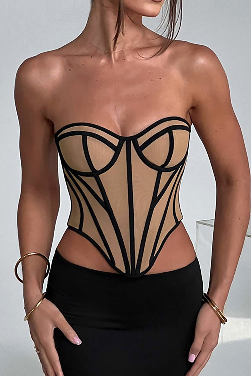 A woman wearing a tan and black geometric corset with her hands on her hips.