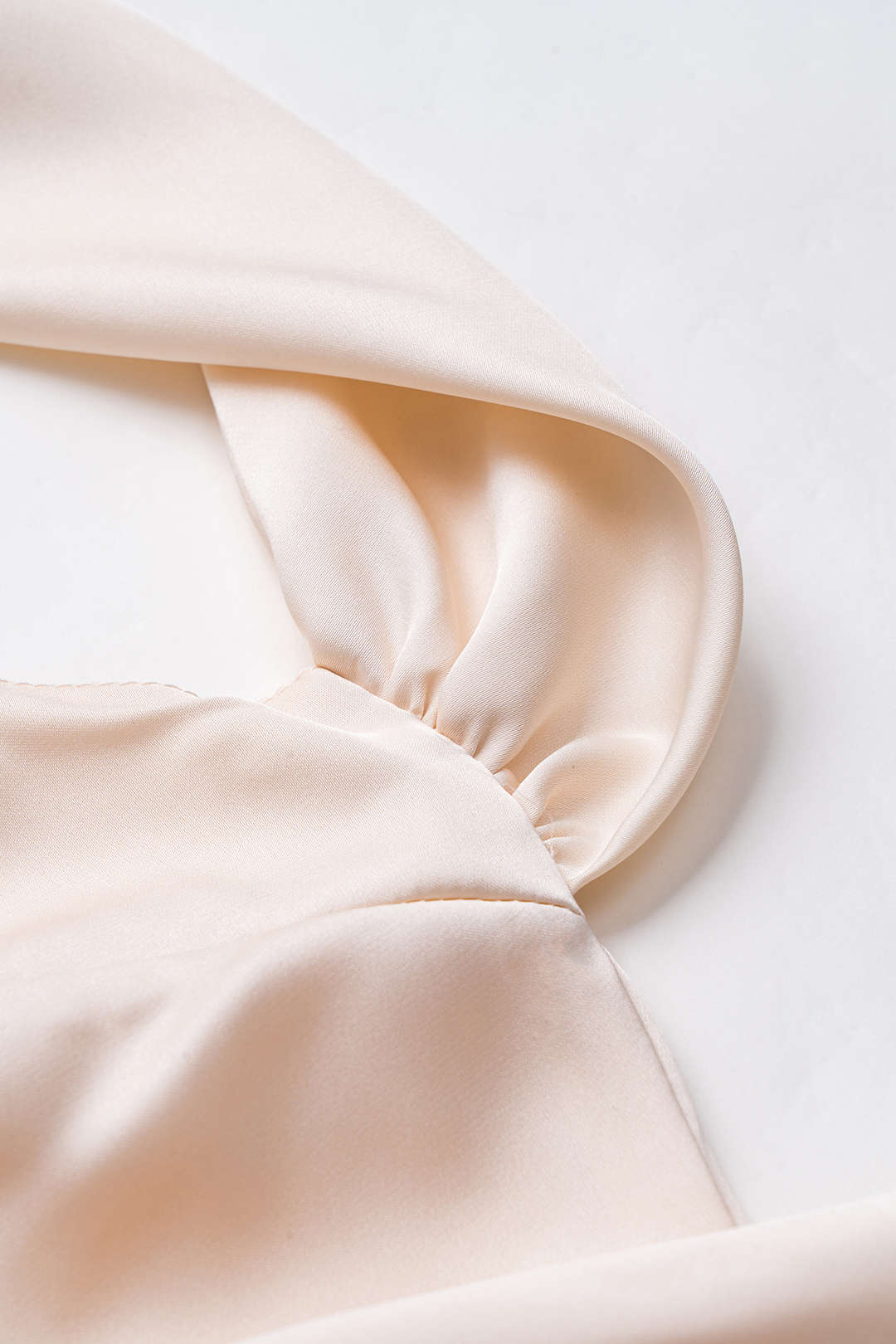 Close-up of the gathered sleeve detail on a cream satin dress.