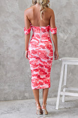 Back view of a woman in a pink and red floral print ruched midi dress