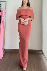 Woman holding a silver clutch while wearing a coral evening gown.