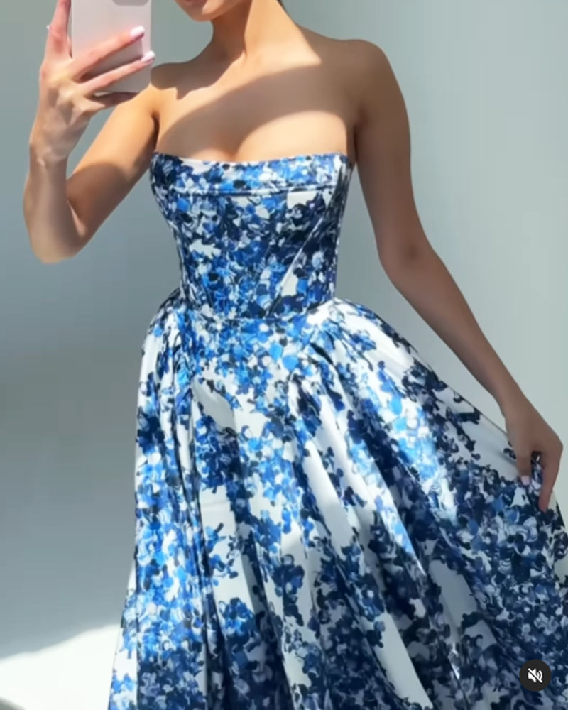 Close-up of a woman in a strapless blue and white floral print ball gown, holding her phone.