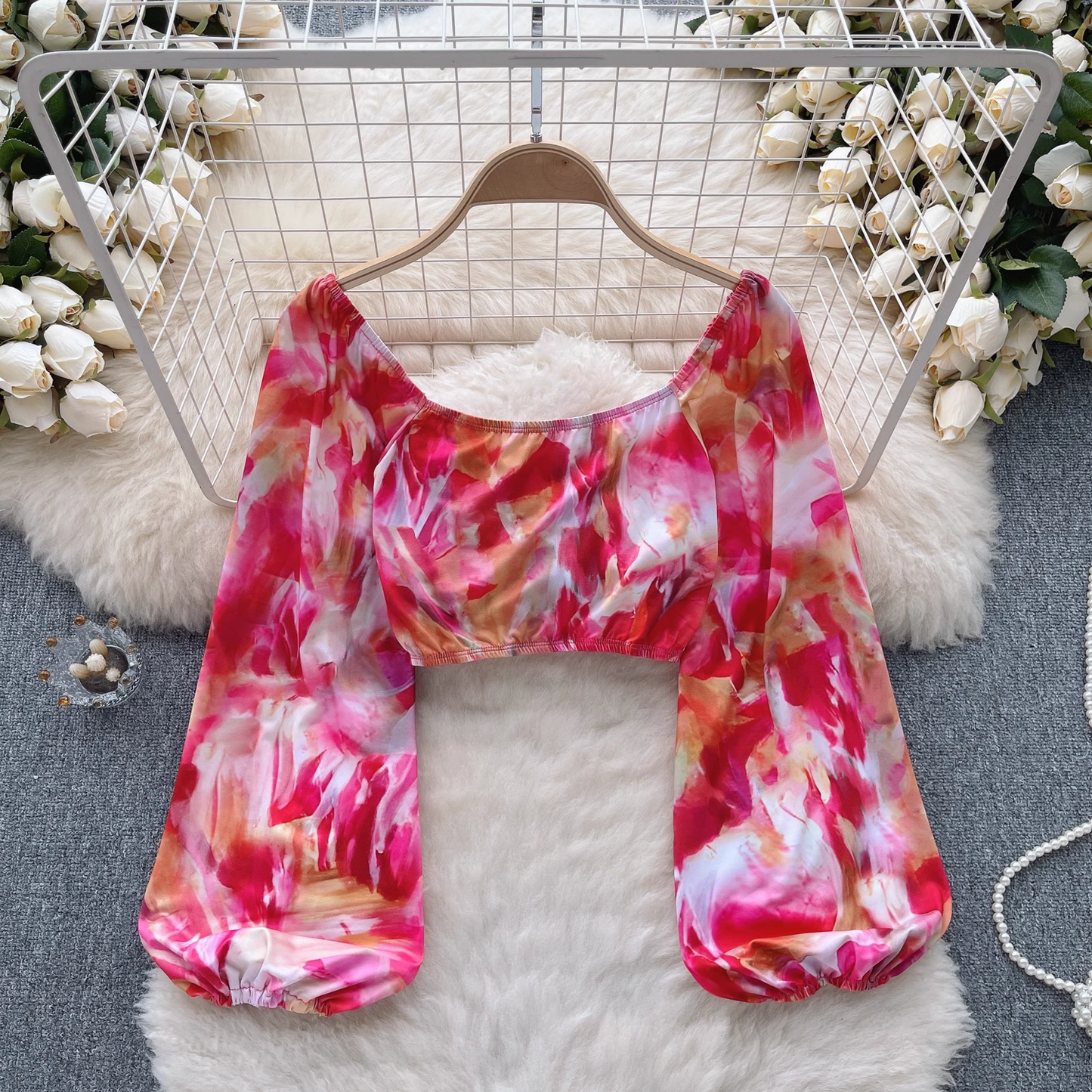 Full view of a cropped tie-dye print top with a sweetheart neckline and long, billowy sleeves.