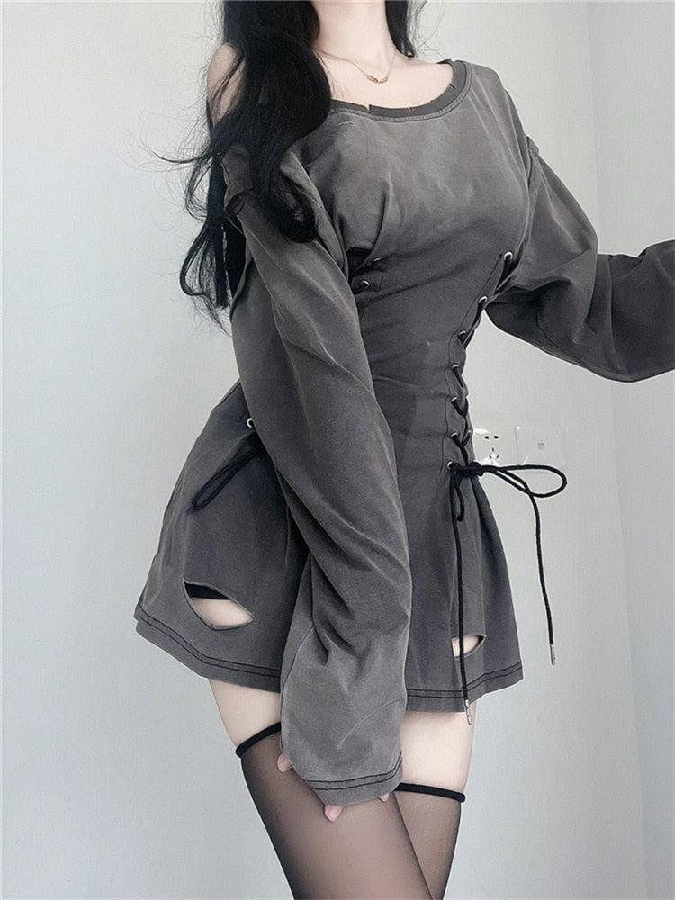 Woman posing in a gray off-the-shoulder dress with lace-up details and black thigh-high stockings.