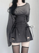 Back view of a woman wearing a gray distressed dress with a lace-up corset waist and black stockings.