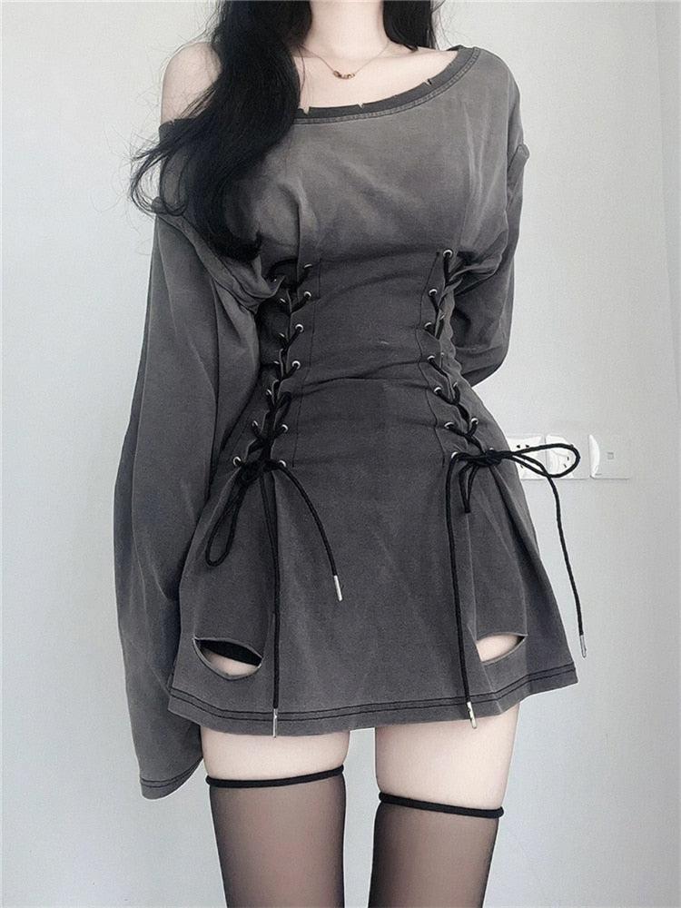 Back view of a woman wearing a gray distressed dress with a lace-up corset waist and black stockings.