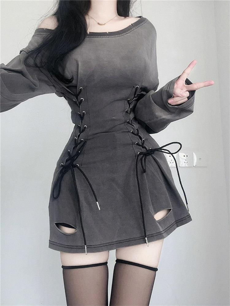 Woman wearing a gray off-the-shoulder long-sleeved dress with a lace-up corset waist and distressed details.
