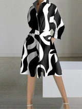 A woman wearing a black and white abstract print shirt dress