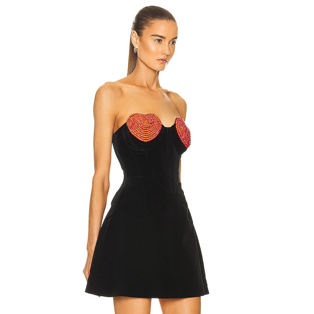A side view of a model wearing a black strapless dress with red heart embellishments.