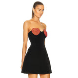 A side view of a model wearing a black strapless dress with red heart embellishments.
