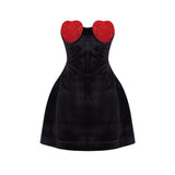 A black strapless dress with red heart embellishments on the bust and a flared skirt.