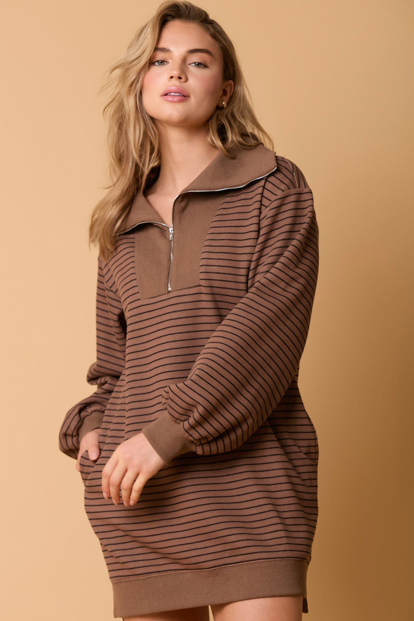 Woman wearing a striped sweater dress with a large brown collar and quarter zip in brown and navy stripes.